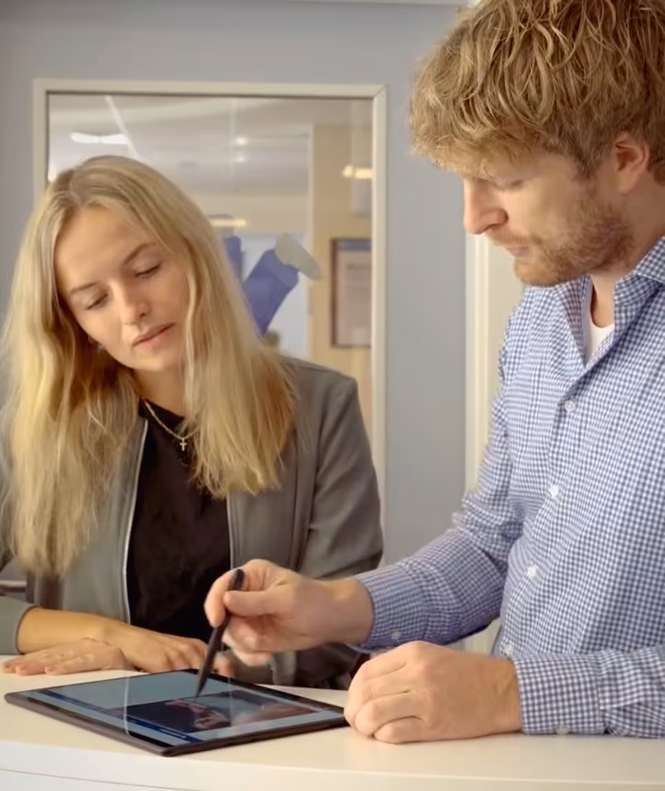 Sebastian Deden und eine Mitarbeiterin in den Büroräumen des SHK-Betreibs Kreatec blicken auf ein Tablet und stimmen die eingesparten Kosten durch den Einsatz der epostbox ab.