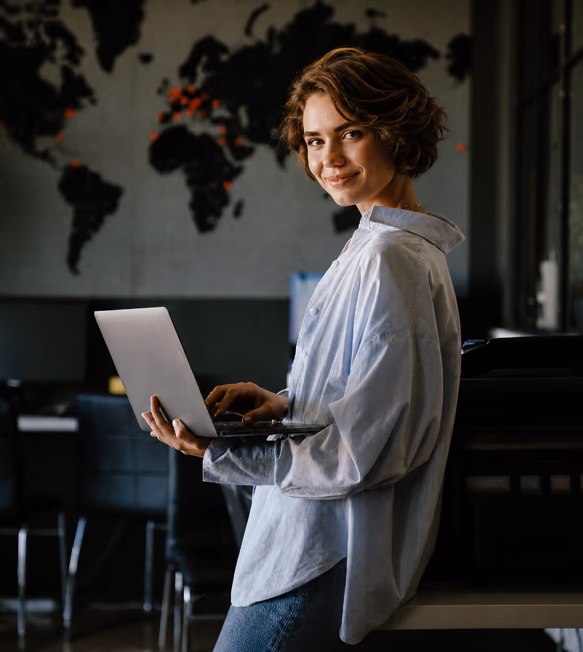 Eine junge Frau steht in einem Büro mit dem Laptop in der Hand und lächelt in die Kamera. Sie kann Ihre Arbeitszeit wieder wertschöpfend einbringen, weil sie mit der epostobx viele manuelle Prozesse im Postausgang einspart.