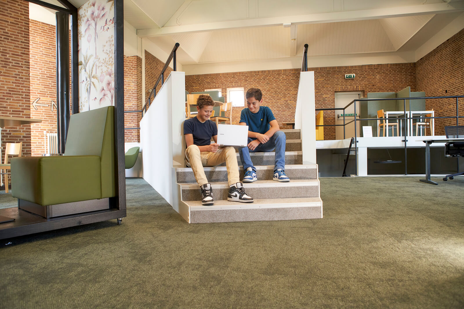 Leerlingen op de trap bezig met hun laptop