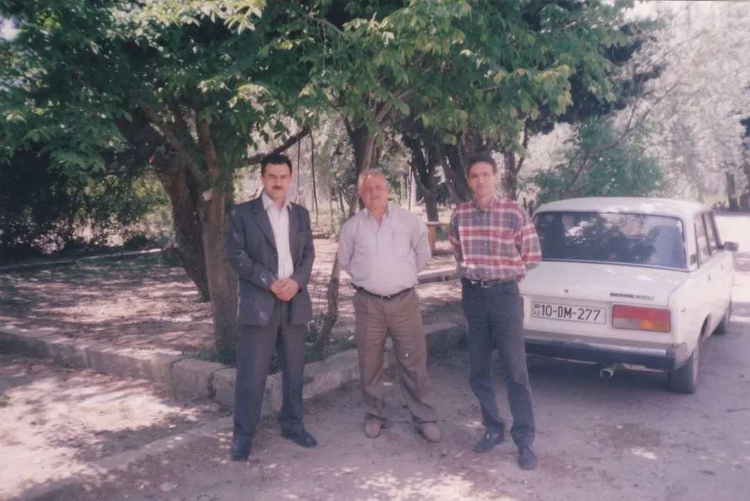 A group of men standing next to each other in front of a car.