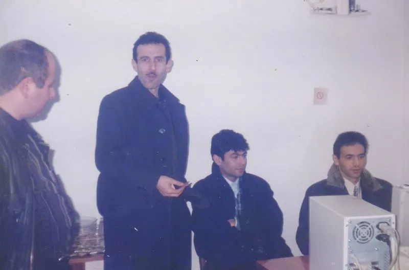 A group of men standing around a computer.