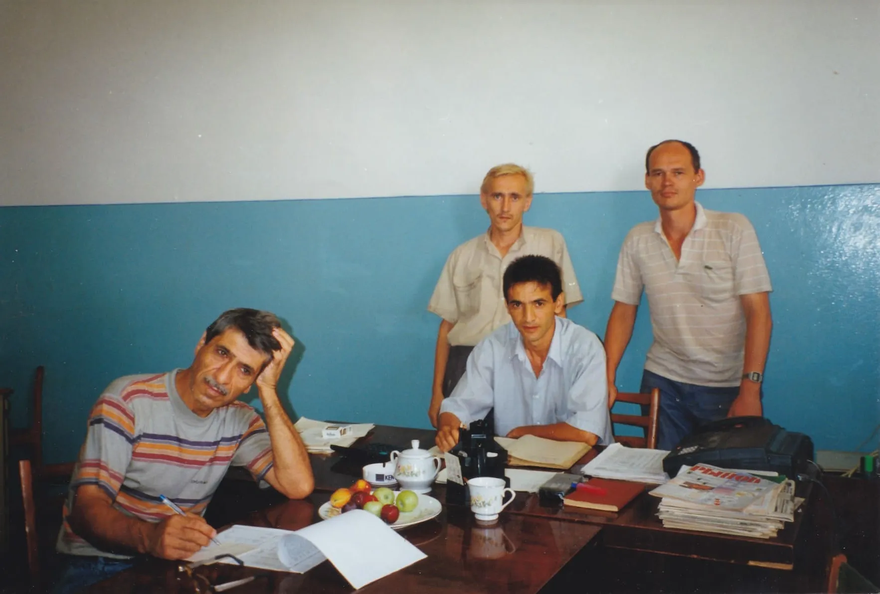 A group of men sitting around a wooden table.