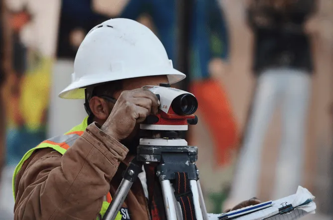 A man wearing a hard hat looking through a telescope.