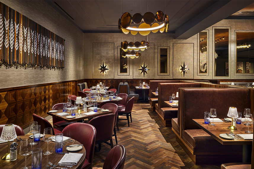 Cozy upscale restaurant interior with leather chairs, wooden tables, and warm lighting fixtures.