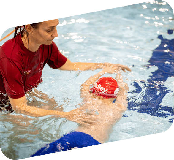 I swimming teacher helping a child to learn to swim