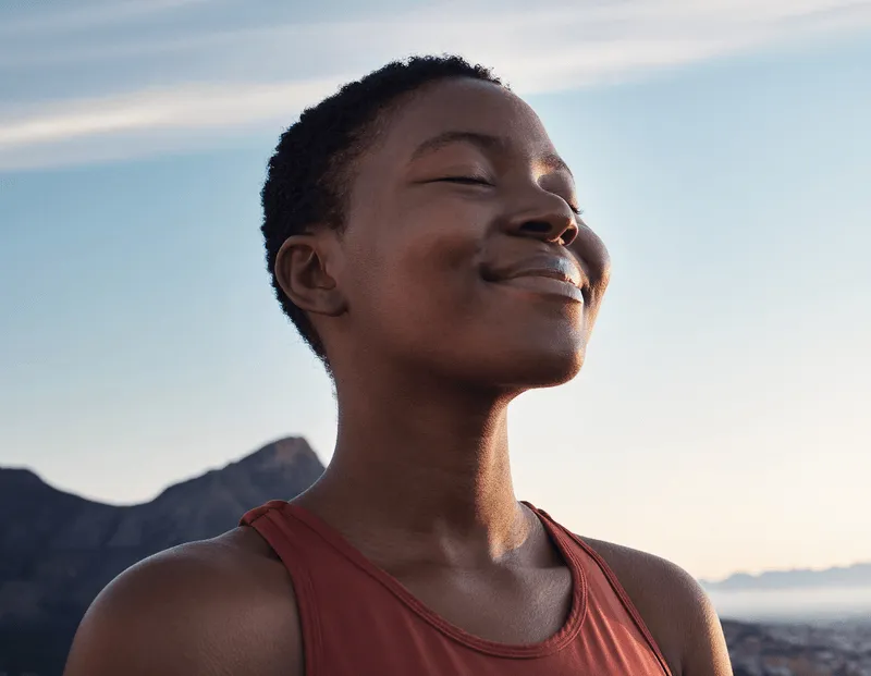 A woman smiling with mountains in the background.