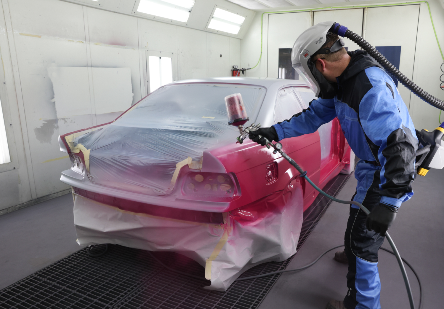 Technician spraying a car with a new coat of automobile paint