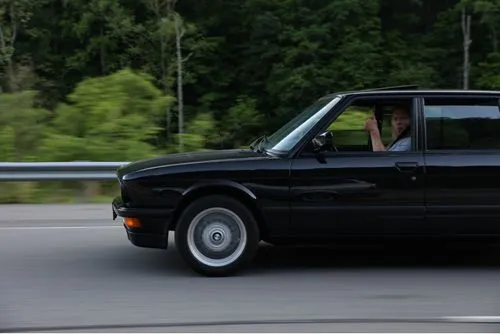 Driver giving a thumbs-up in a black vintage BMW