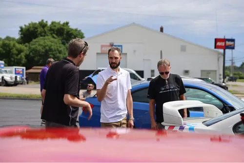 Enthusiast Auto employees gathered around a vintage BMW