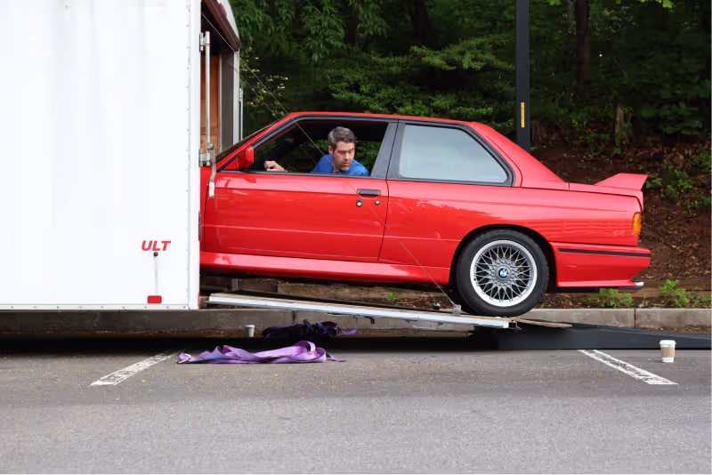 Enthusiast Auto co-owner unloading a vintage red BMW from a moving truck