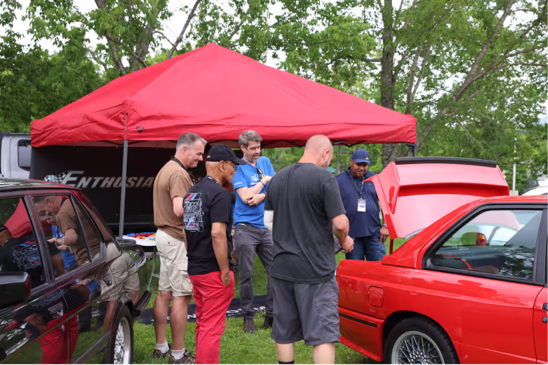 Event attendees gather around a pristine vintage BMW