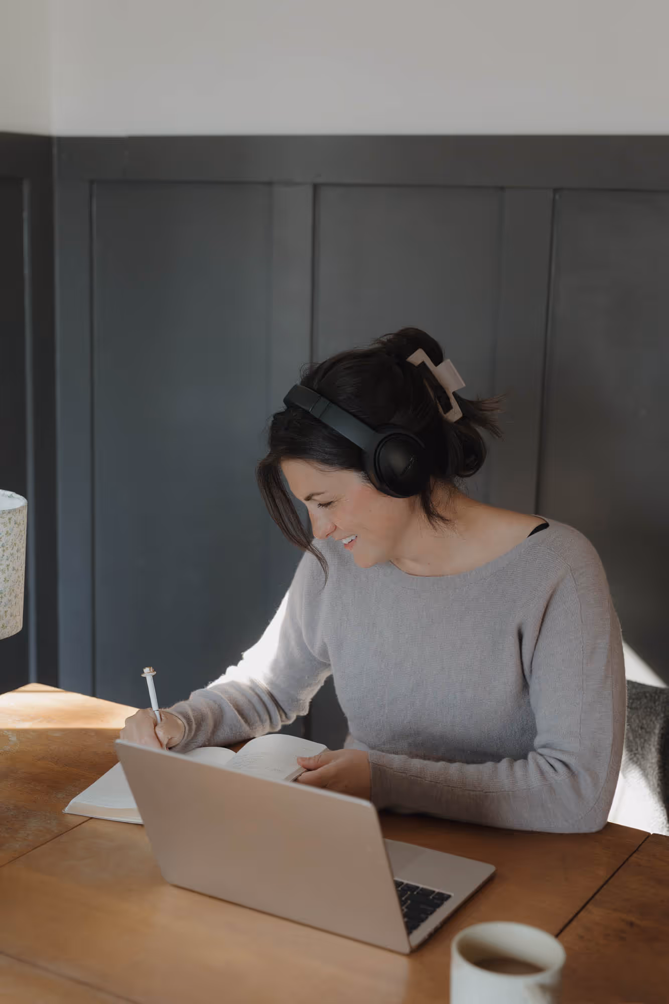 Devyn sat at desk with headphone on, writing in her notebook.