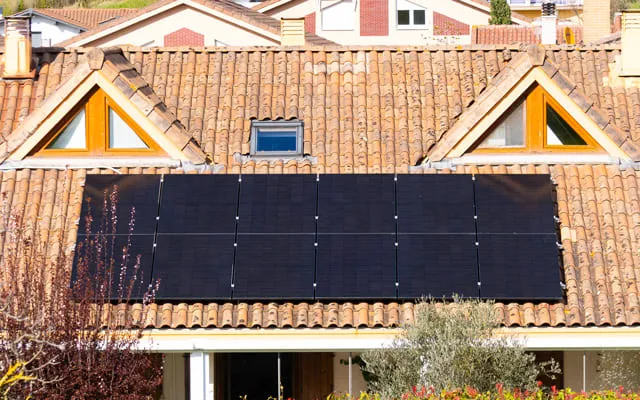 Nahaufnahme einer modernen Photovoltaikanlage auf einem Ziegeldach eines Wohnhauses.