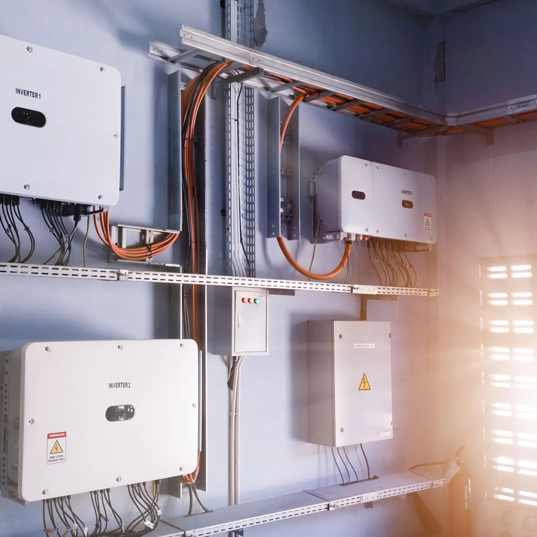 Eine Reihe von Wechselrichtern und Verkabelungen an einer Wand, Teil einer Solaranlage zur Speicherung von Energie.