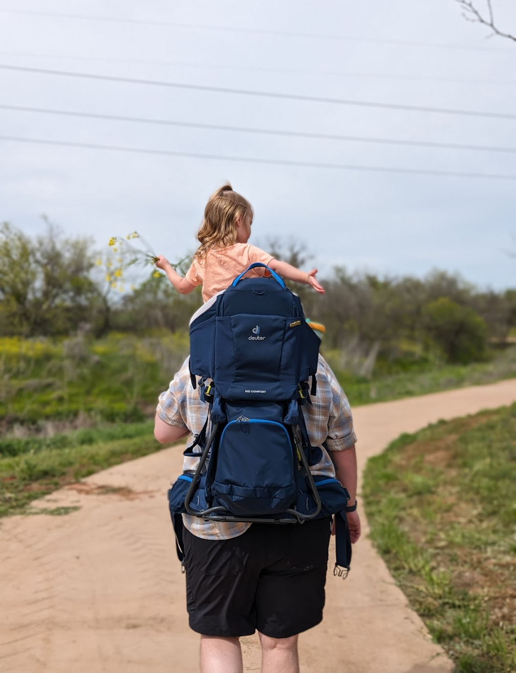 man backpacking with little girl on shoulders