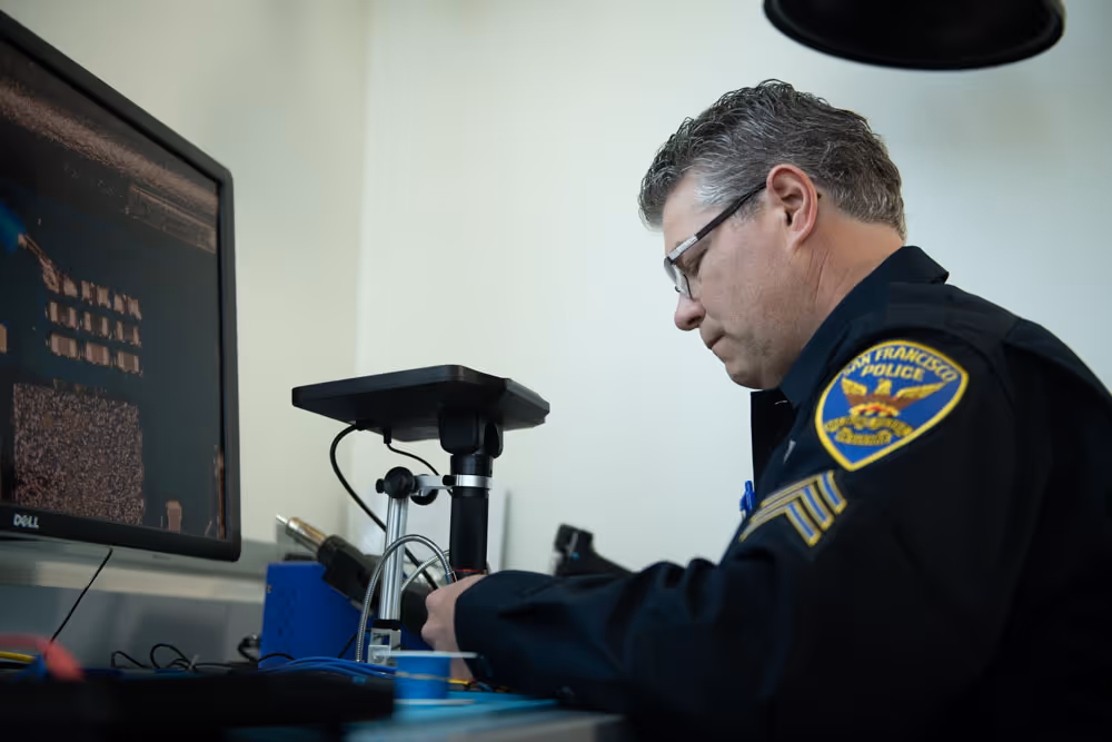 A male officer examining with microscope