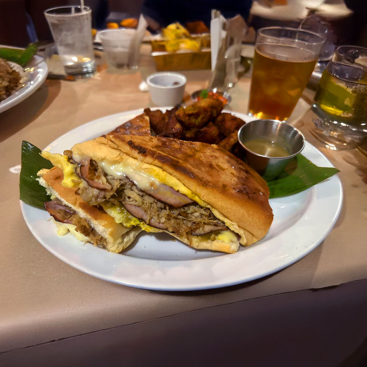 A Cuban sandwich with fried plantain slices on the side.