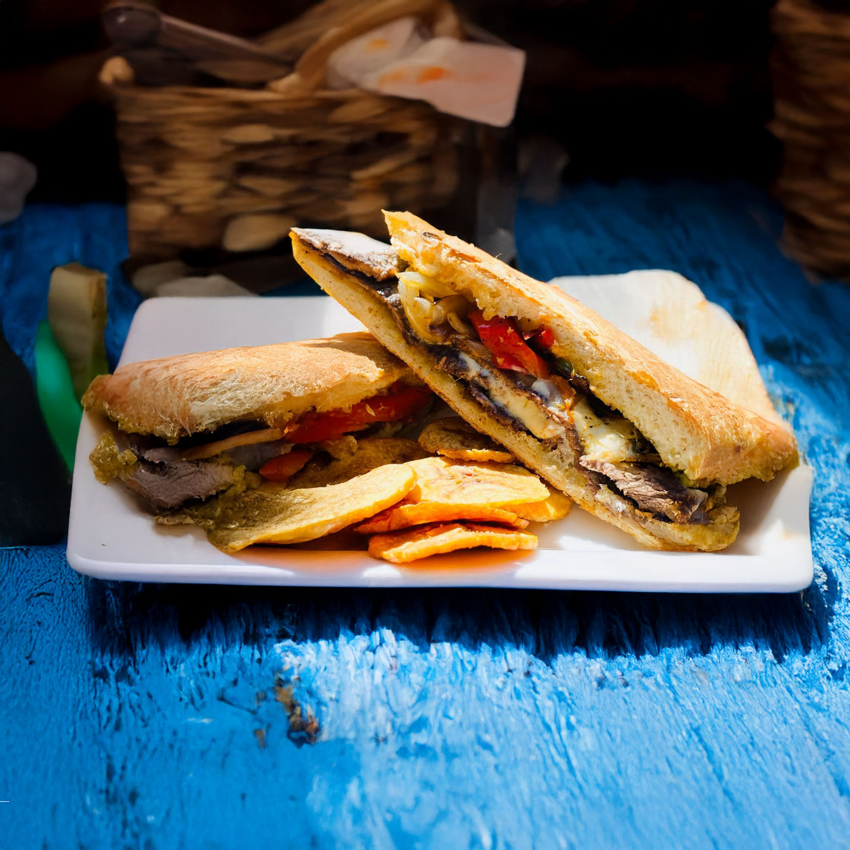 A Cuban sandwich with fried plantain slices on the side.