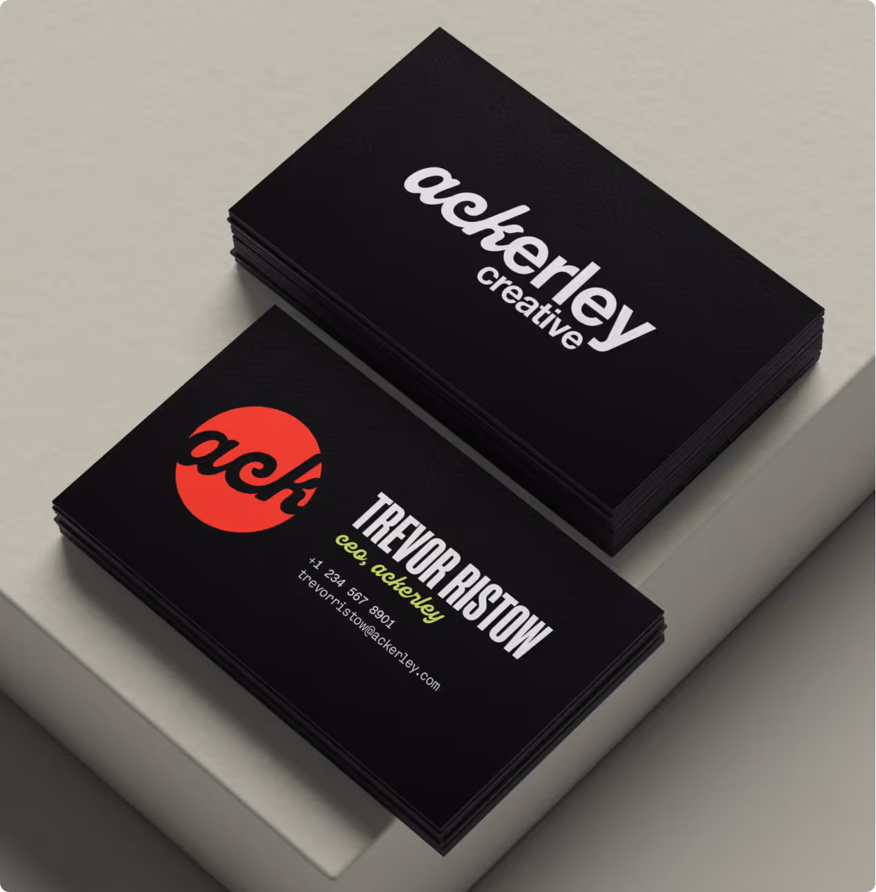 Two stacks of black business cards on a light surface with 'ackerley creative' and contact info for Trevor Ristow.