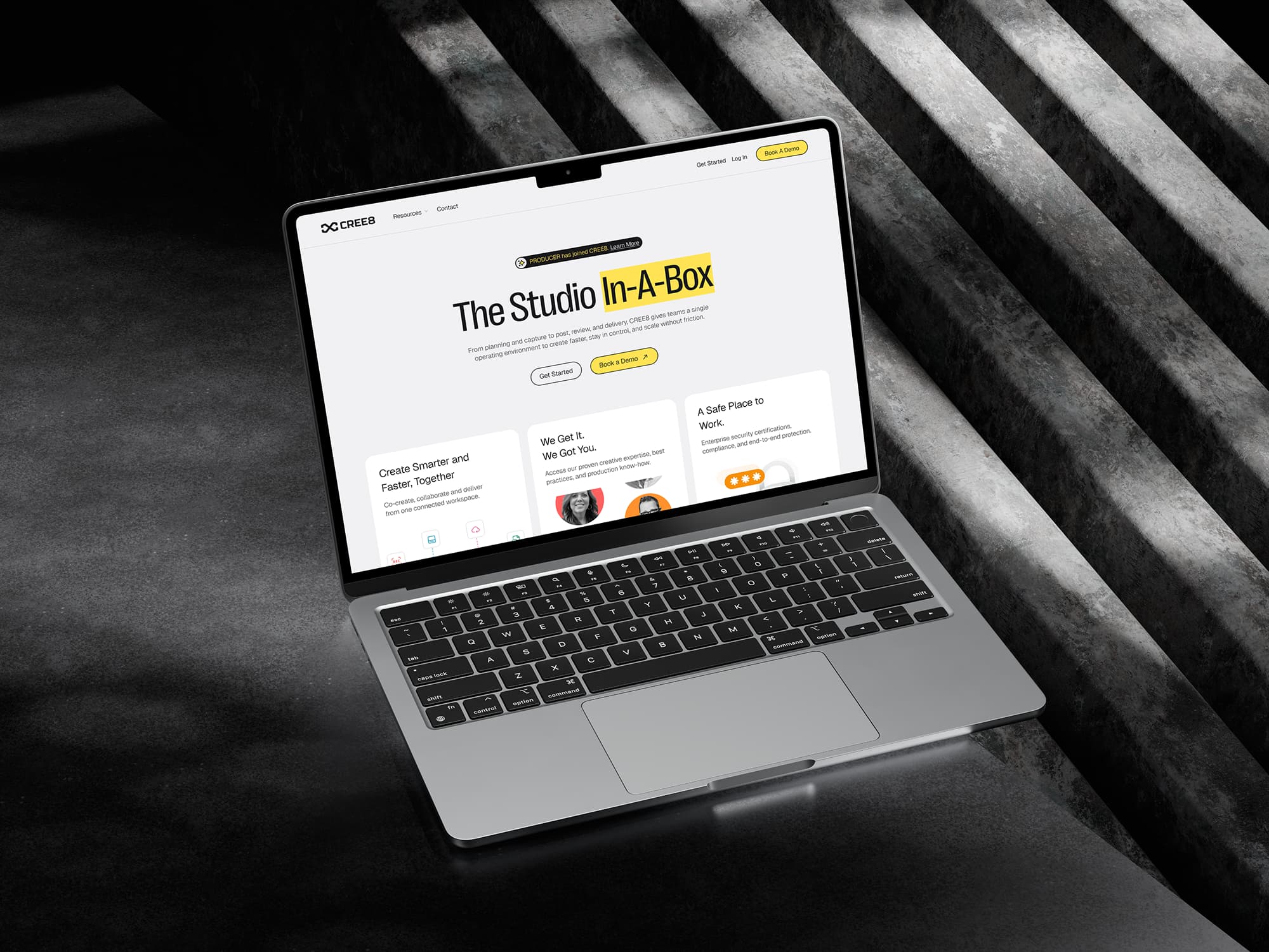 Open laptop on dark textured surface displaying CREE8 website homepage with the text 'The Studio In-A-Box' and navigation options.