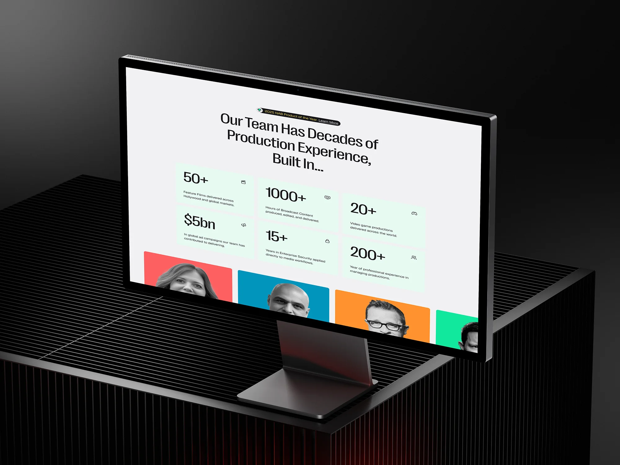 iMac 24-inch angled view displaying a webpage showcasing team production experience statistics and headshots.