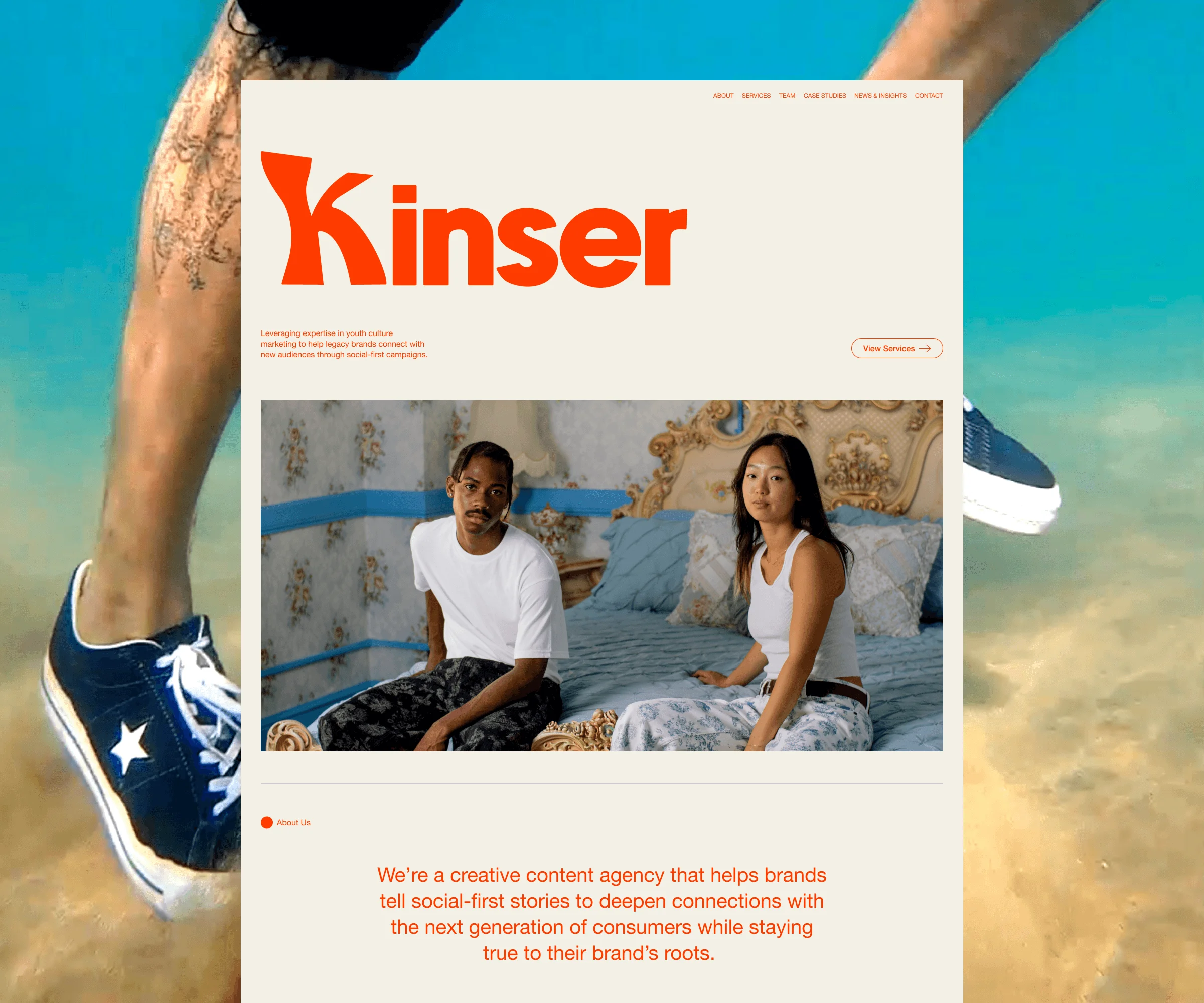 Open laptop on a round platform displaying a website with large orange Kinser text and ocean image.