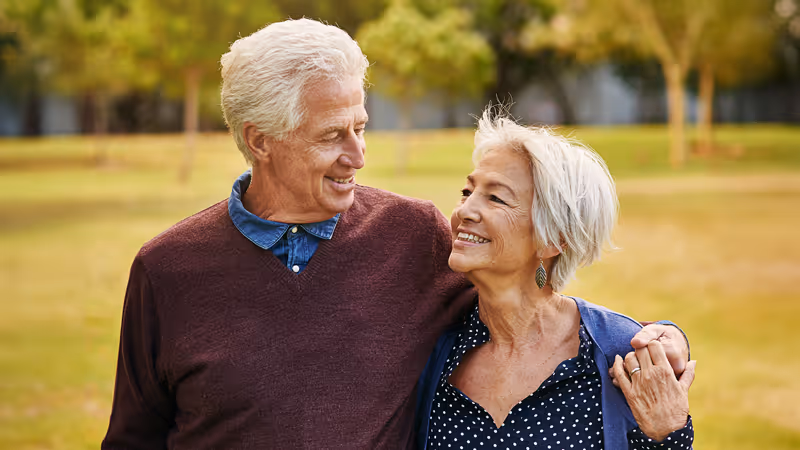 Couple smiling holding each other in a park