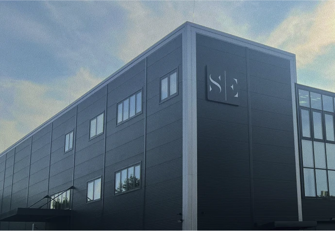 Modern, sötétszürke homlokzatú ipari épület, sarkán a Studio and Conferences logóval, kék ég háttérrel.