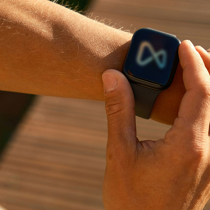Person wearing a smartwatch displaying the Meta logo on its screen.