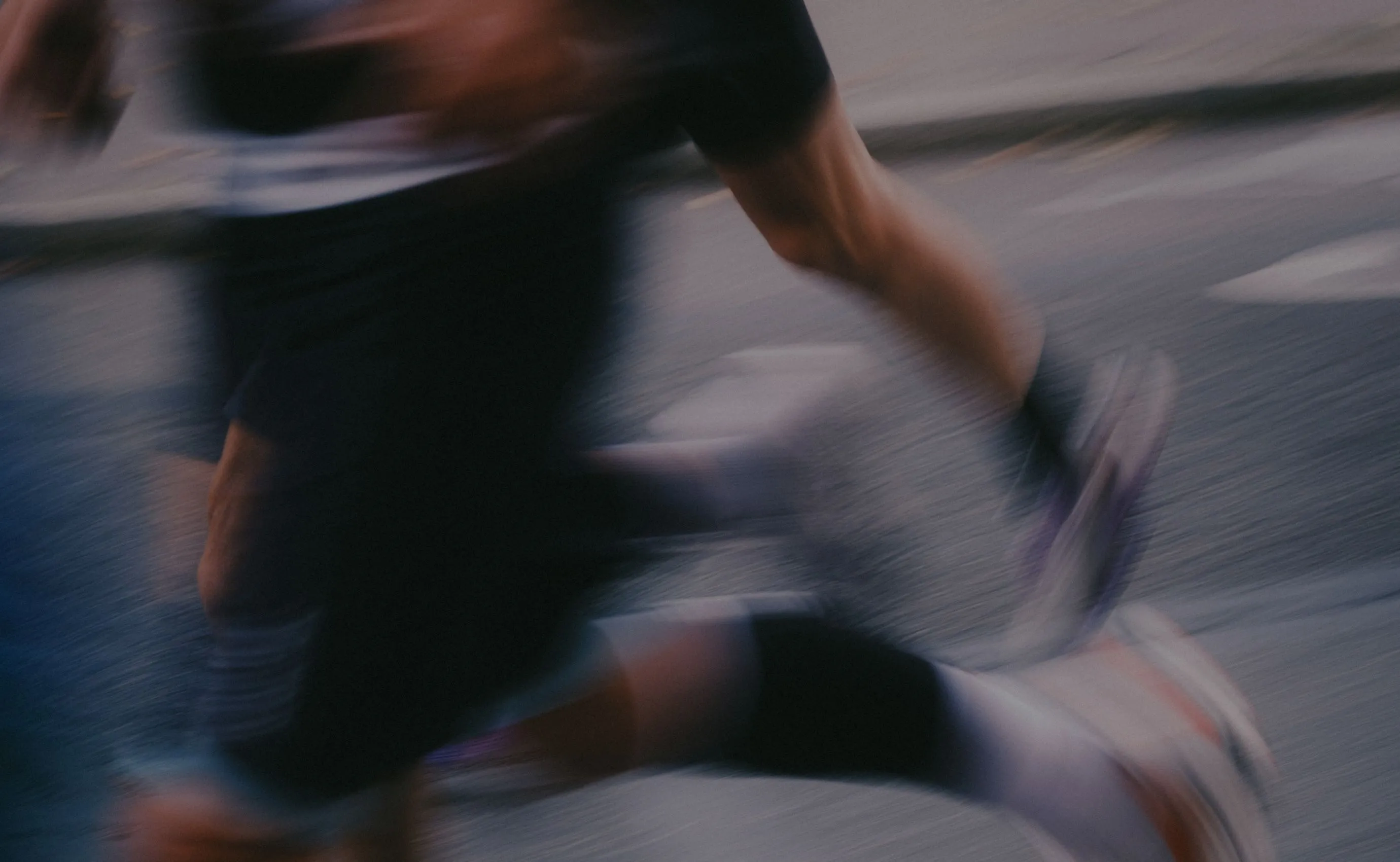 Blurred close-up of a person running on a paved road, emphasizing motion and movement.