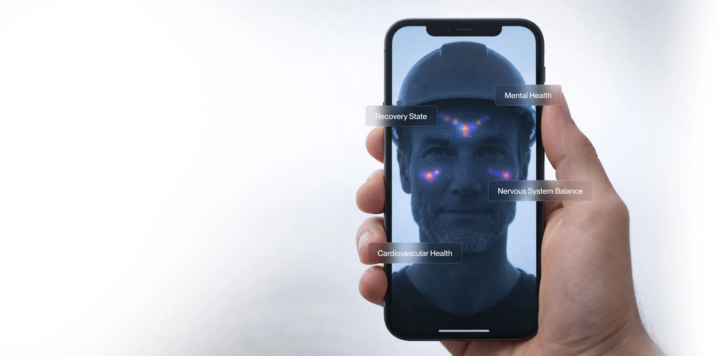 Hand holding a smartphone displaying a man wearing a helmet with facial scan highlights labeled Recovery State, Mental Health, Nervous System Balance, and Cardiovascular Health.