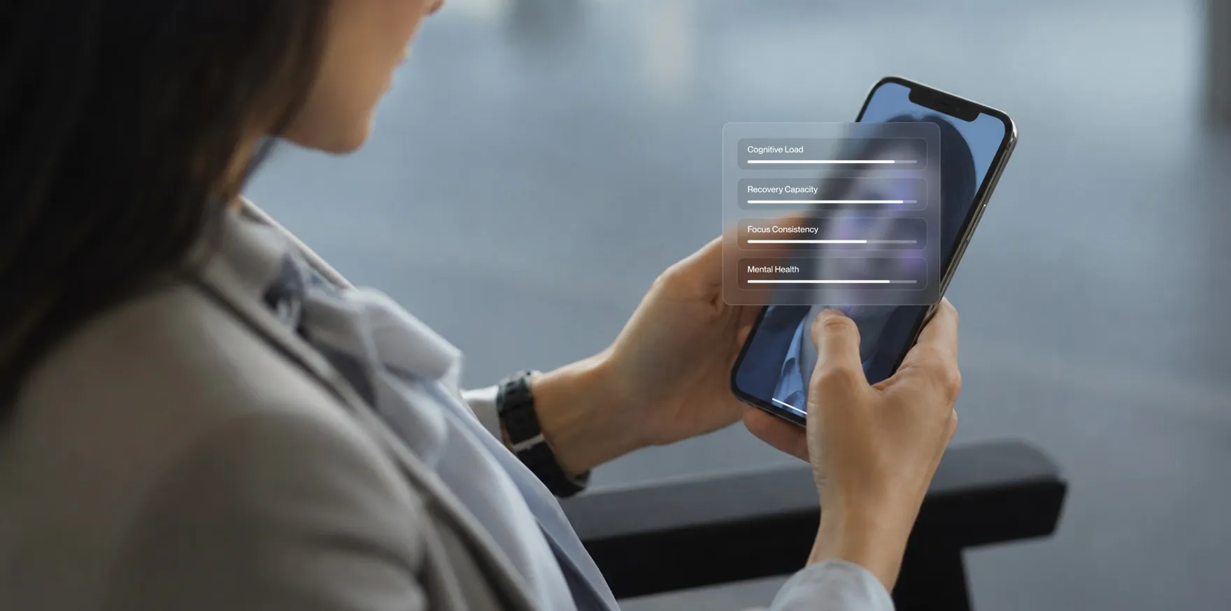 Person holding smartphone with overlay showing cognitive load, recovery, focus, and mental health bars.