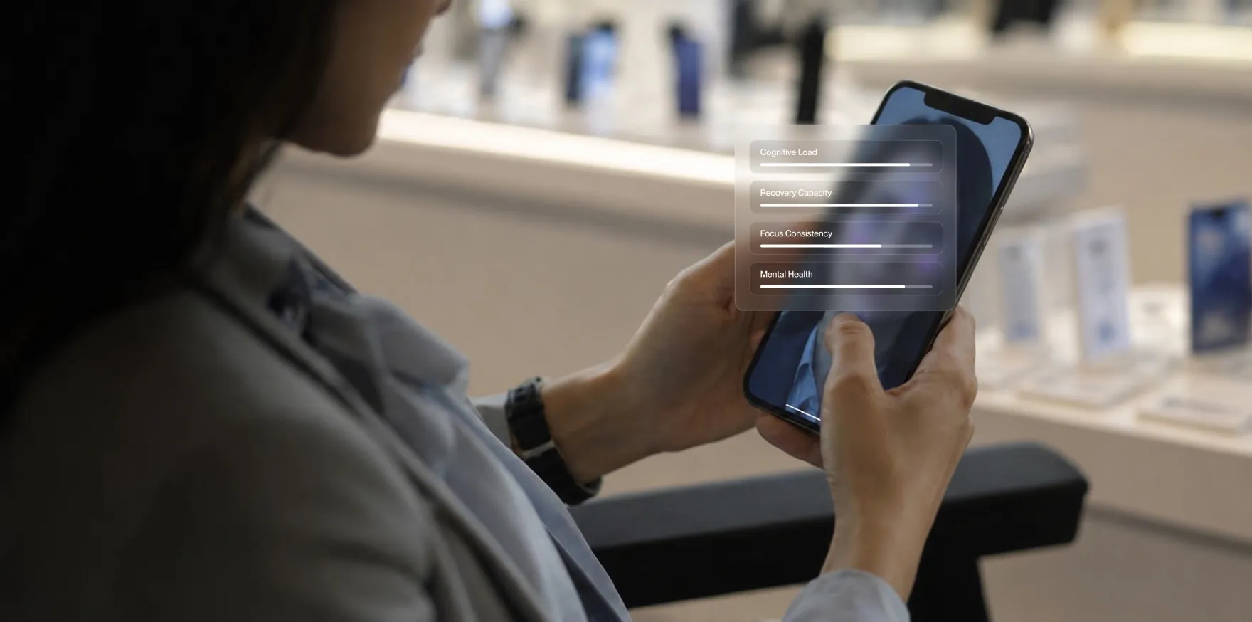 Person holding smartphone displaying cognitive load, recovery capacity, focus, and mental health progress bars.