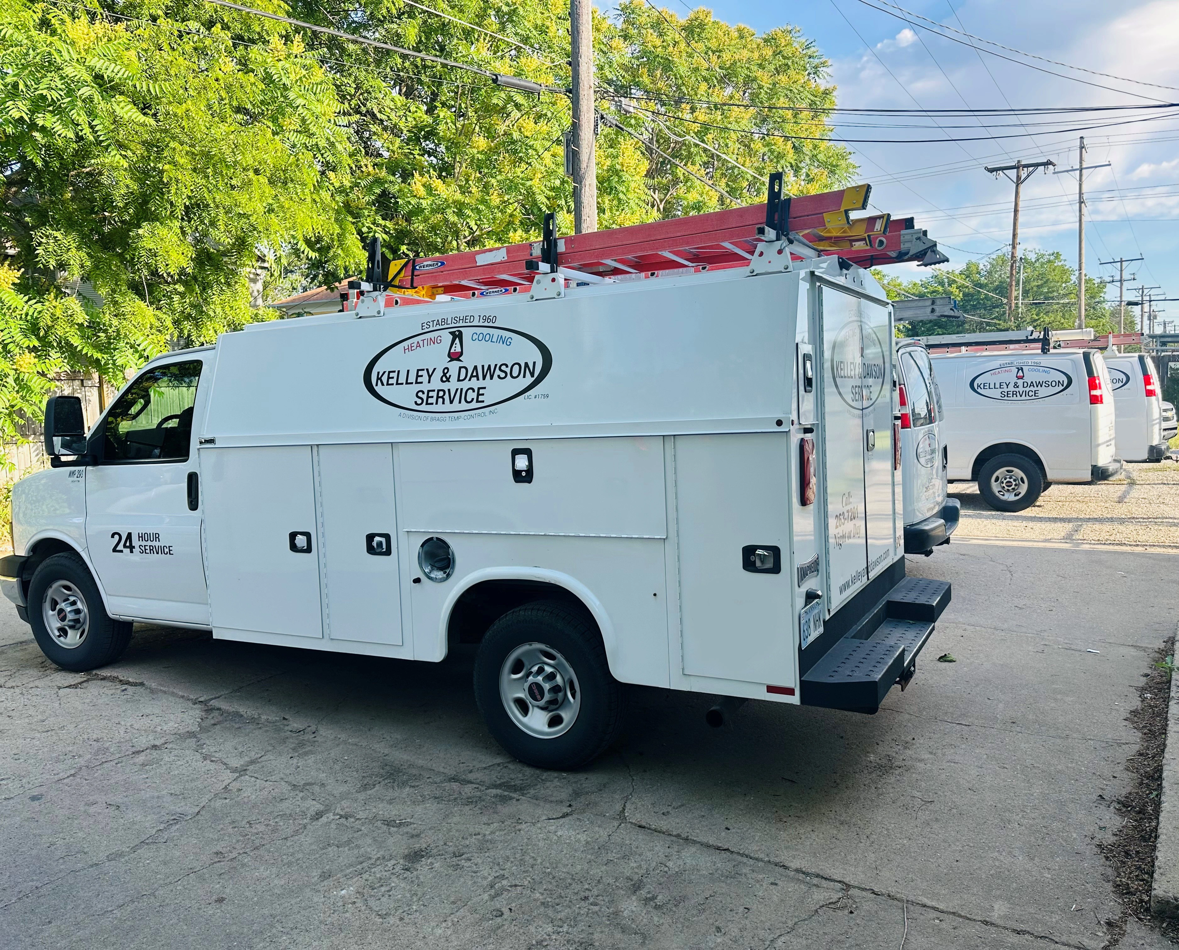 A white service van with "Kelley & Dawson Service" logo and red ladders on top.