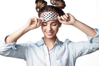 A young woman smiling with a eye mask.
