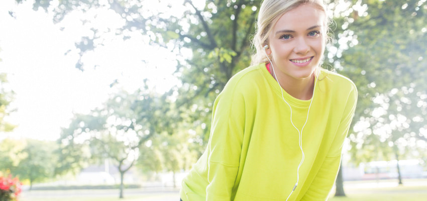 A teenage girl in the park with her earphones in.