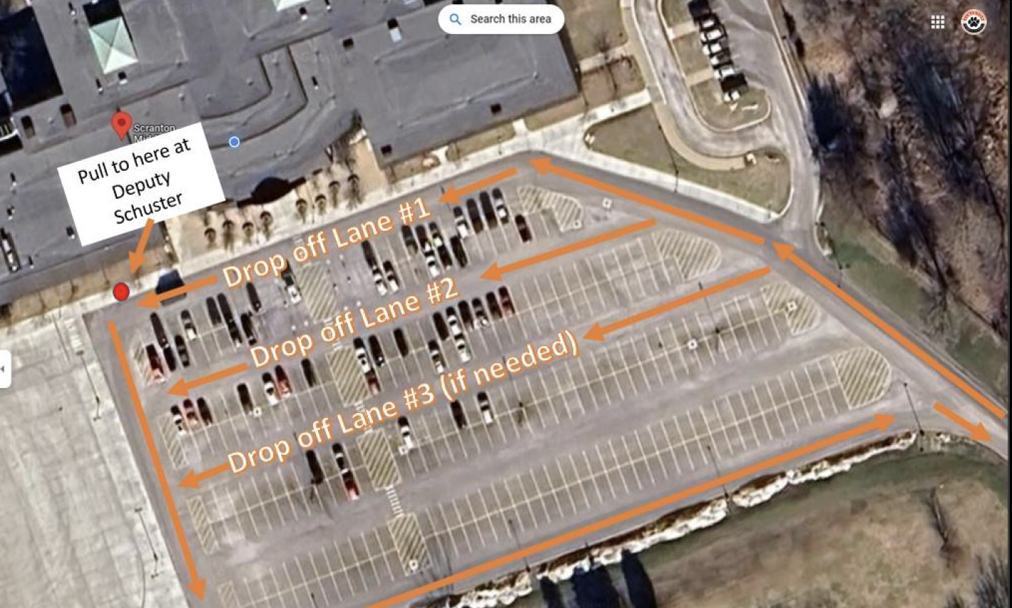 Aerial view of a parking lot with orange arrows indicating three drop-off lanes and instruction to pull to Deputy Schuster location marked by a red dot.