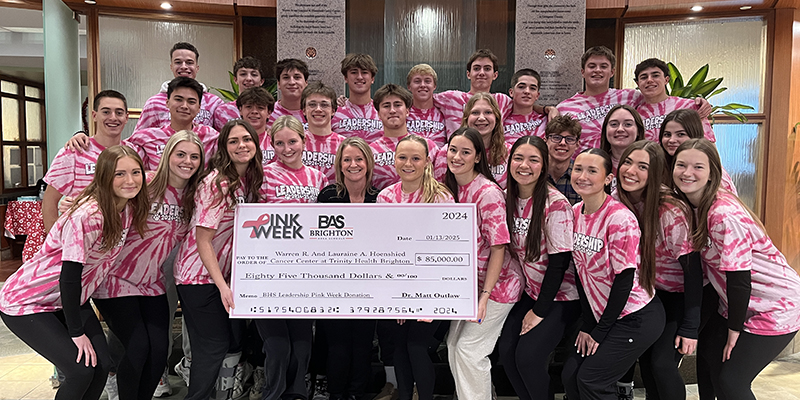 Group of young people wearing pink tie-dye leadership t-shirts holding a large check for $85,000 made out to the Warren R. and Lorraine A. Hospield Cancer Center.