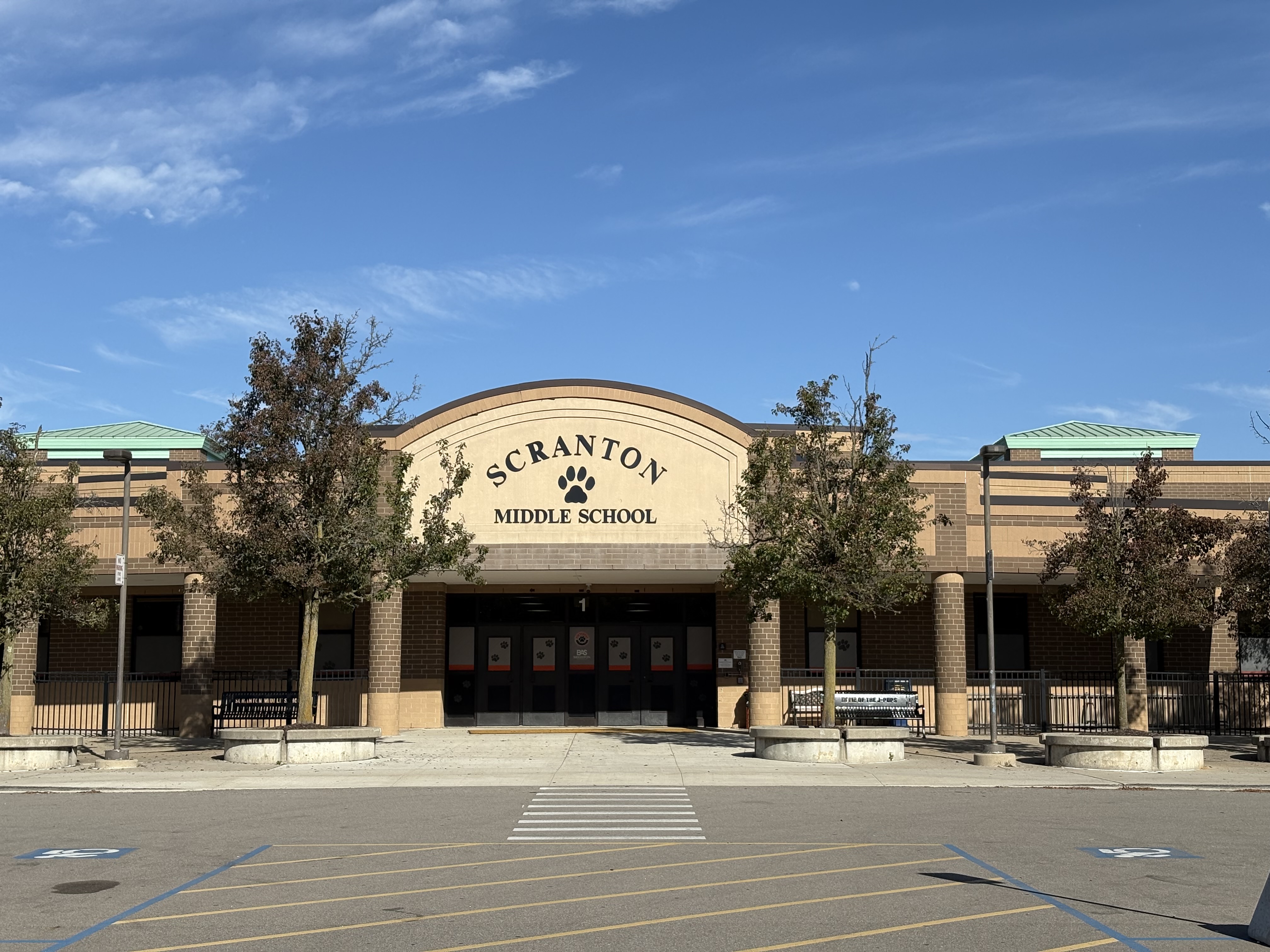 Entrance of Scranton Middle School building with trees and benches in front under a clear blue sky.