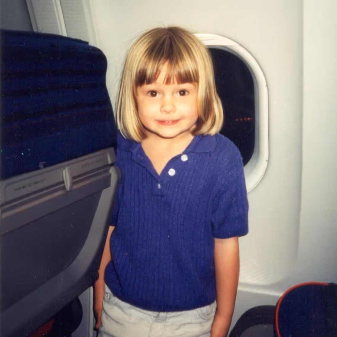 Jackie Pulice of 851 Travel as a young girl standing in an airplane.
