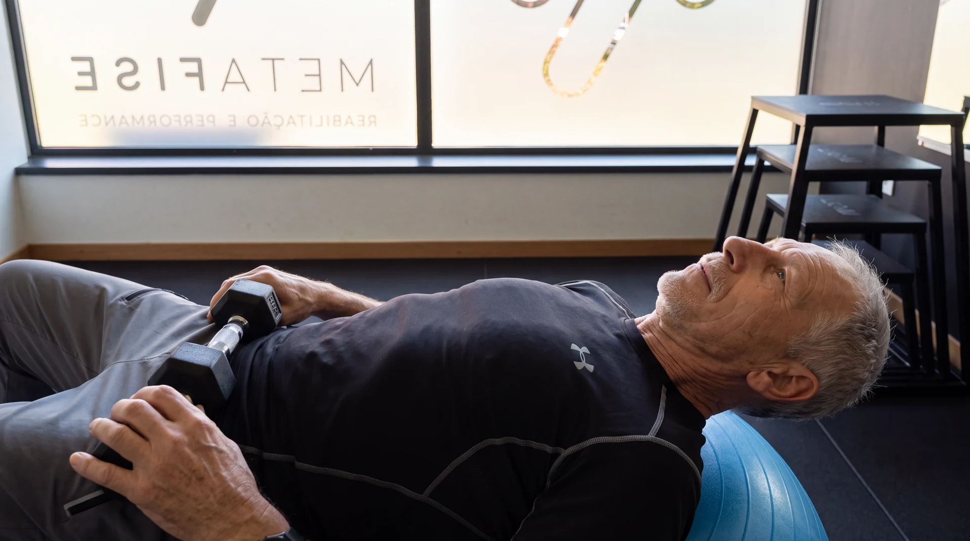 Utente realiza um exercício no colchonete com apoio de uma bola.