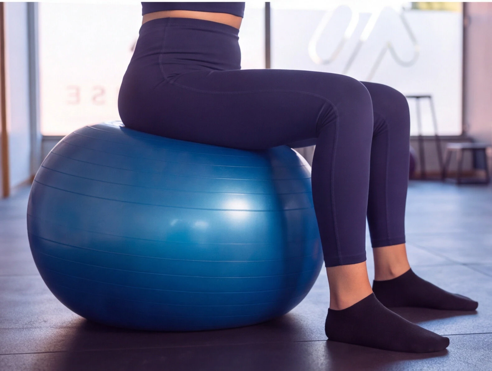 Pormenor da posição sentada numa bola de Pilates.