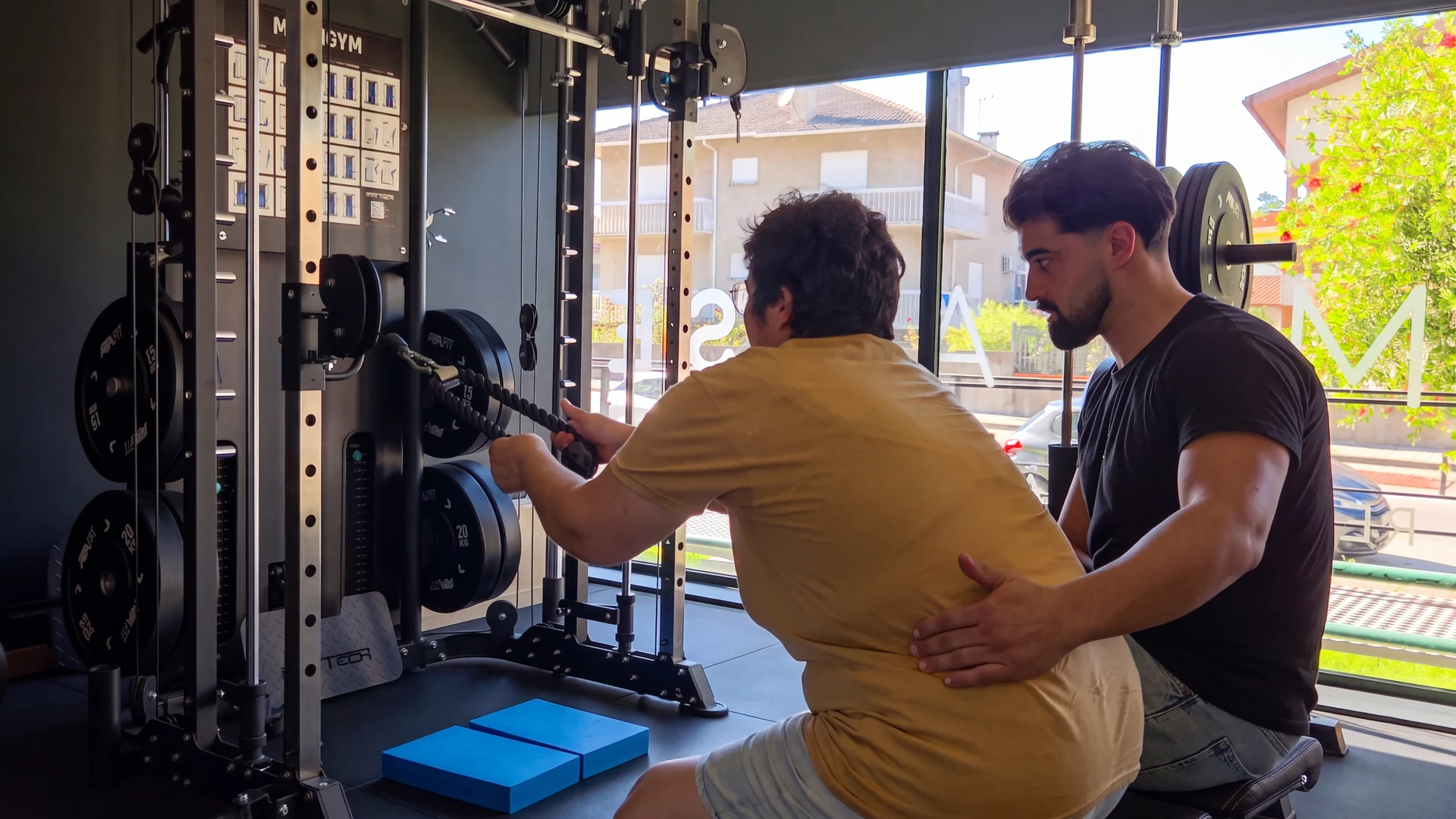 Utente realiza um exercício no ginásio com apoio próximo do fisioterapeuta.