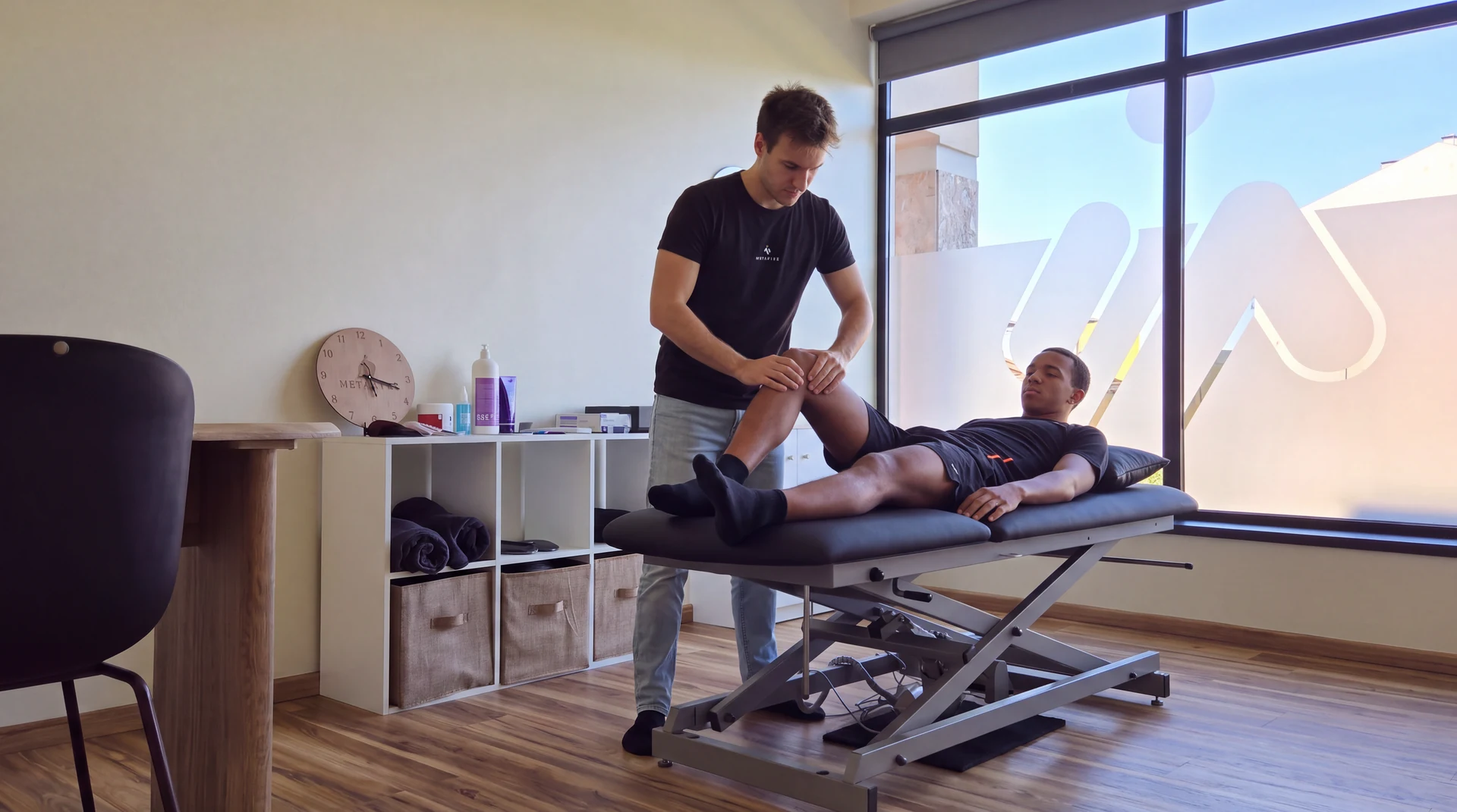 Fisioterapeuta mobiliza a perna de um atleta na marquesa.