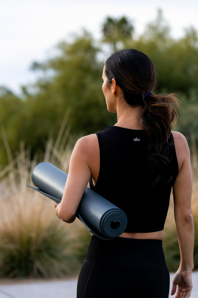 commercial photo of woman walking outside with a yoga mat