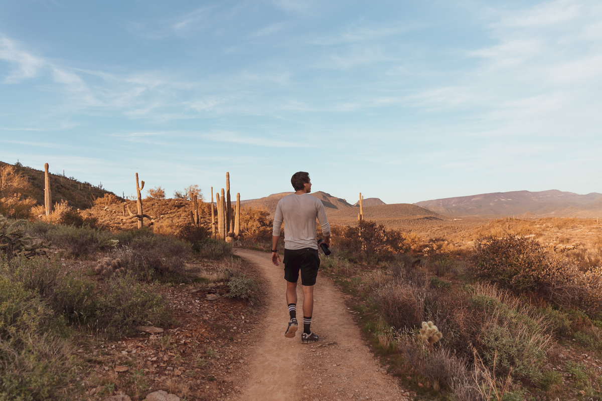 commercial photo of a man walking on a path in the desert