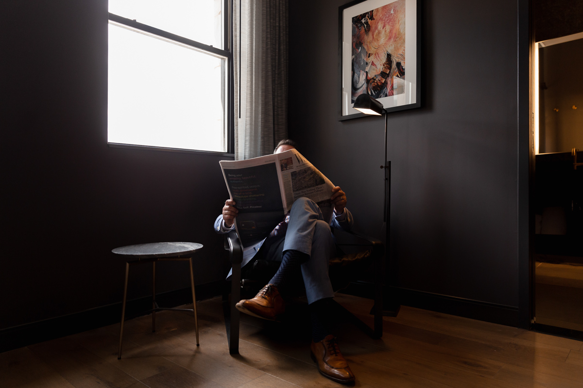 commercial photography of a man reading a newspaper by a window 
