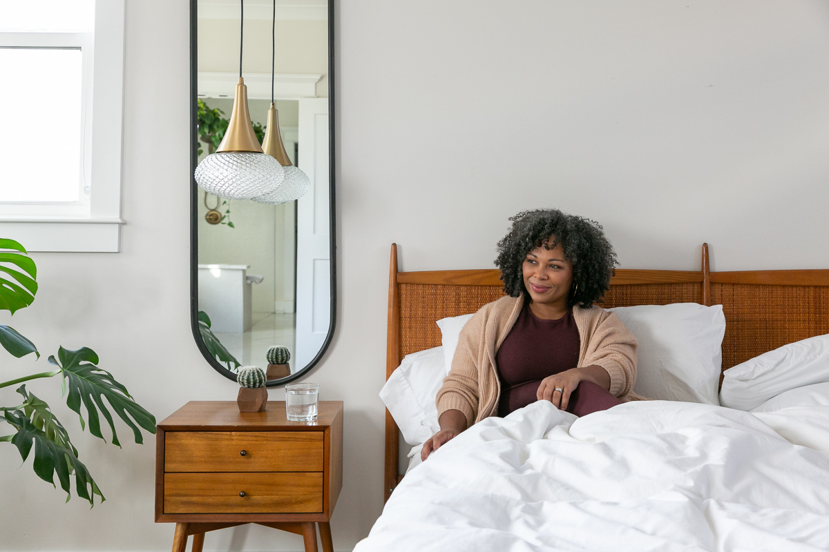 commercial photography of a woman sitting in bed with modern furniture