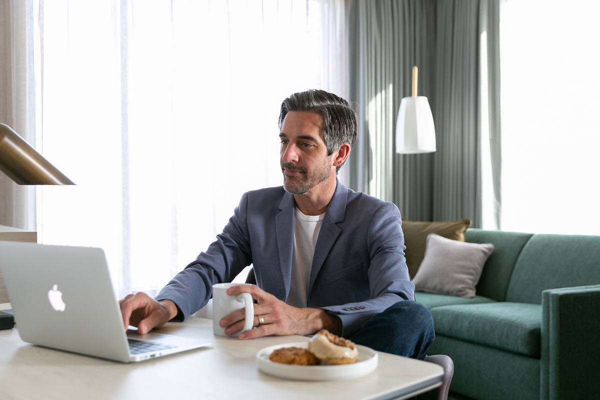 commercial photography of a man working on his laptop in a hotel room