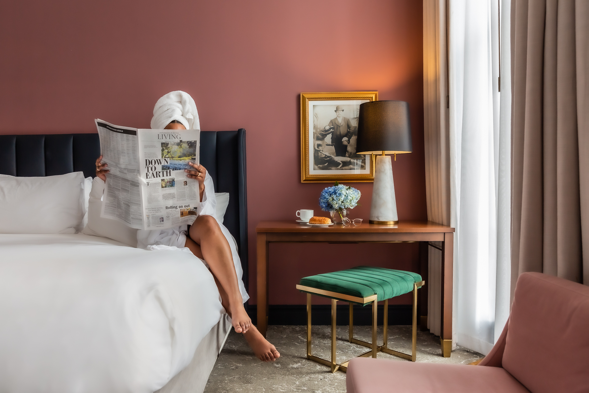 commercial photo of woman reading newspaper in hotel room